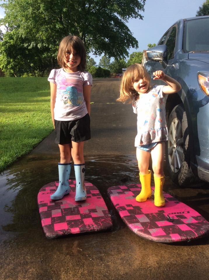 Picture of my two girls standing on boogie boards in the driveway, demonstrating their creativity.