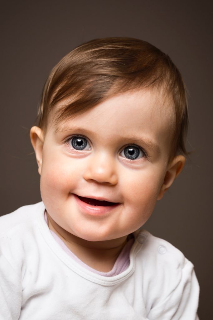 A picture of a baby with a big head, chubby cheeks, and round eyes.