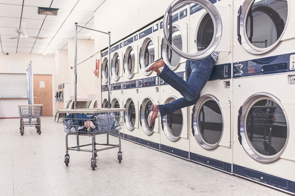 Picture of a woman's feet hanging out of a clothes dryer. 