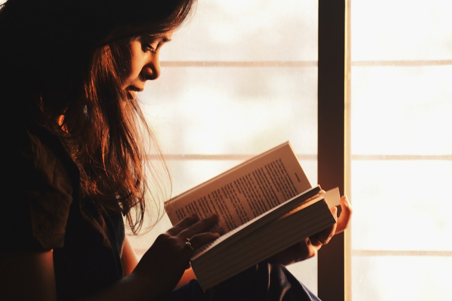 Picture of a woman reading by the window. 